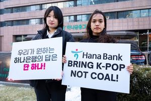 Lee Da-yeon dan Nurul Sarifah memegang papan bertuliskan tuntutan agar Hana Bank menghentikan pendanaan proyek nikel.