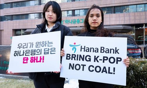 Lee Da-yeon dan Nurul Sarifah memegang papan bertuliskan tuntutan agar Hana Bank menghentikan pendanaan proyek nikel.