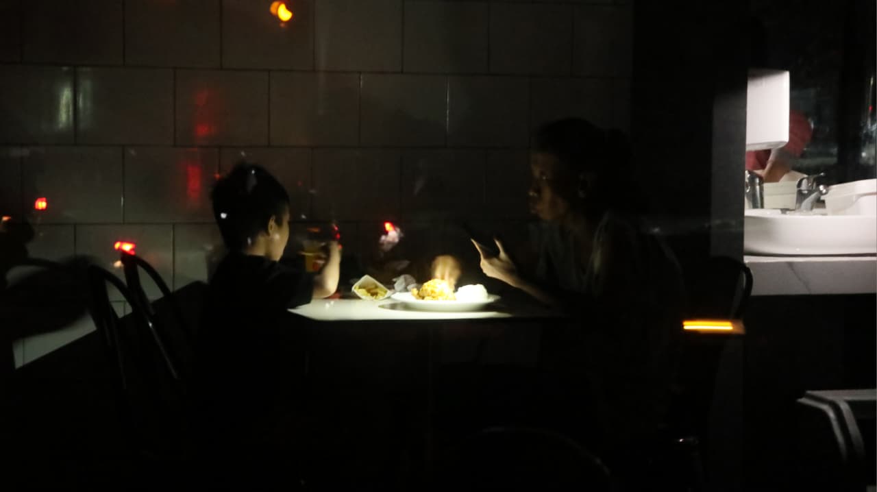 Warga menikmati makan malam di tengah pemadaman bergilir. 