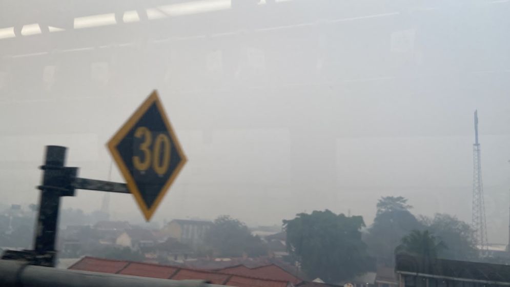 Rumah-rumah dan gedung diselimuti kabut asap pemandangan dari LRT stasiun Garuda Dempo - Demang Lebar daun Senin (20/10/26).